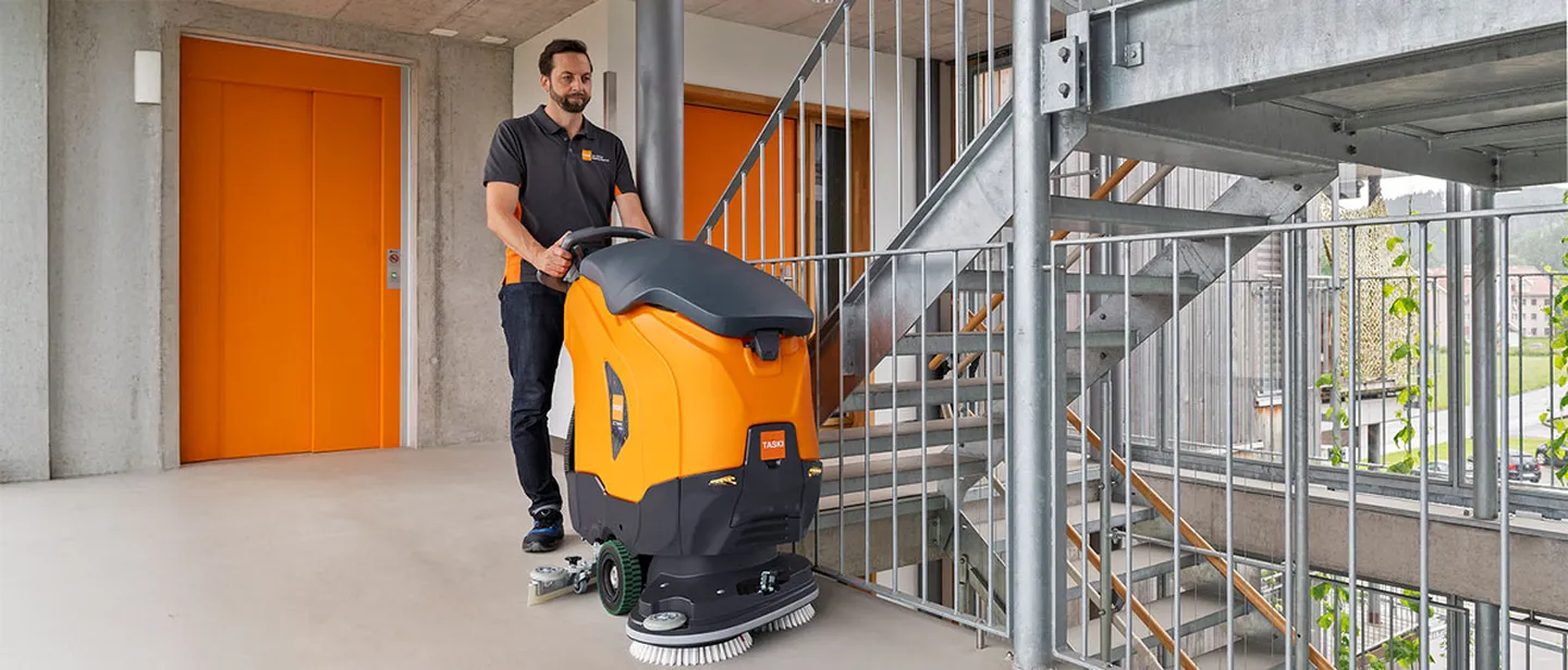 Mitarbeiter mit TASKI-Scheuersaugmaschine in einem Treppenhaus