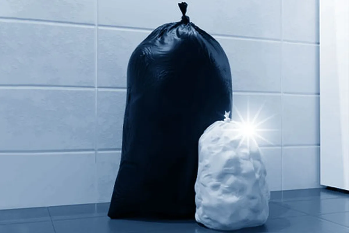 Schwarzer und weißer Müllsack vor Fliesenwand