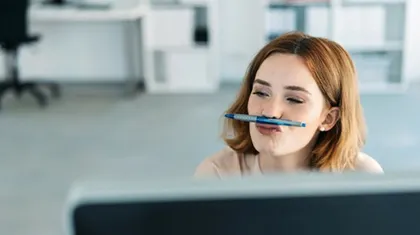 Frau im Büro balanciert einen Stift auf der Oberlippe