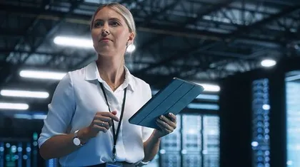 Frau mit Tablet zwischen Serverschränken
