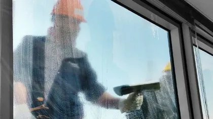 Reinigungskraft putzt ein Fenster mit Abzieher