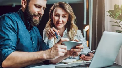 Mann und Frau am Laptop, Smartphone in der Hand