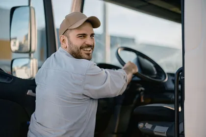 Berufskraftfahrer am Steuer seines LKW, blickt lächelnd zurück